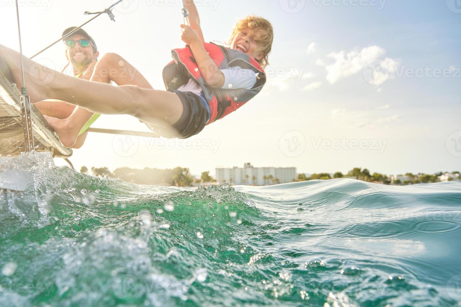 Cheerful boy hanging on rope over sea during trip in sea on cata photo