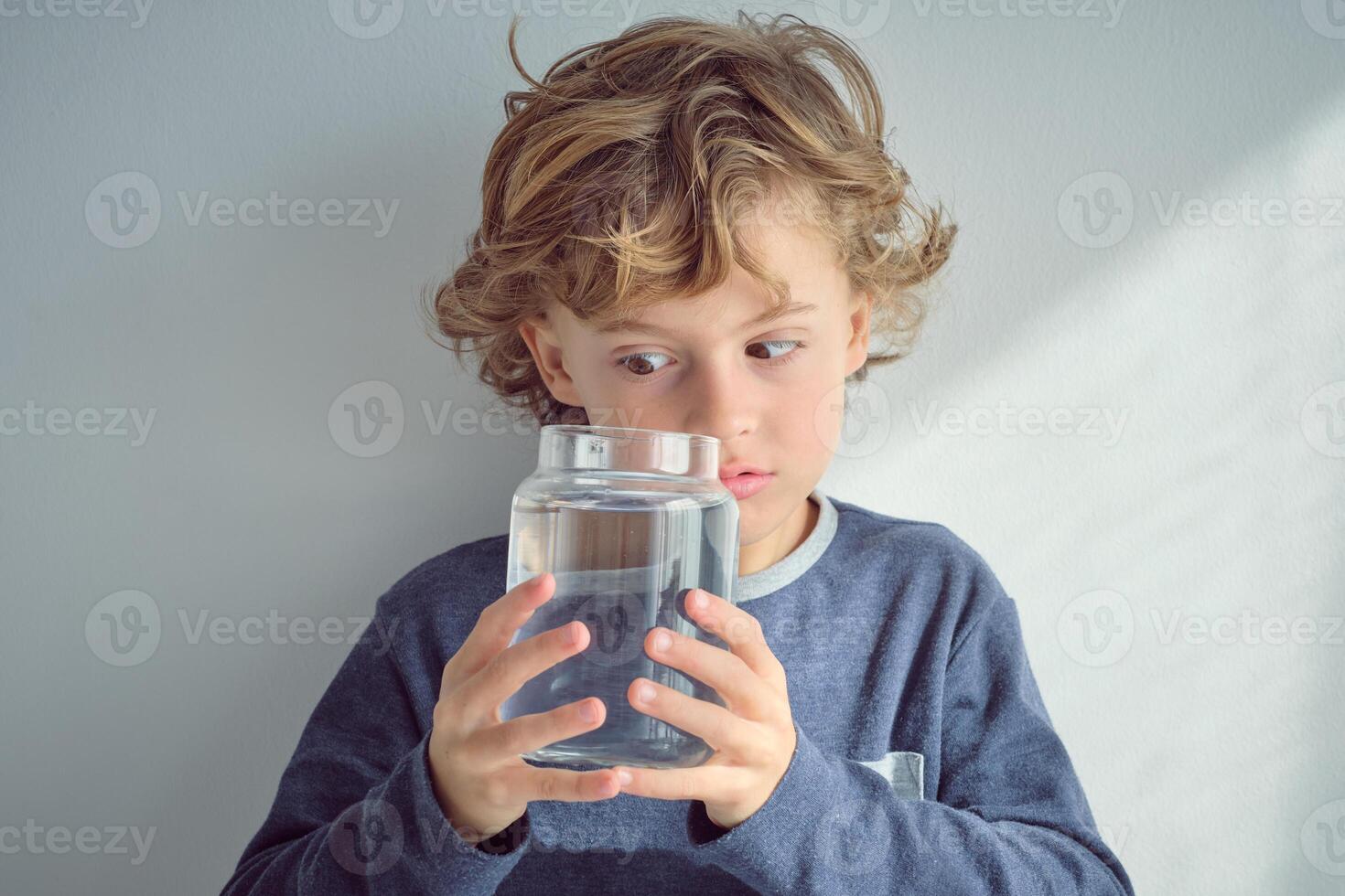 Curious boy looking inside jar with water photo