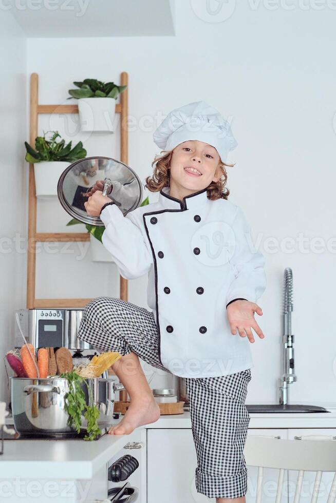 Happy boy in chef uniform with saucepan lid photo