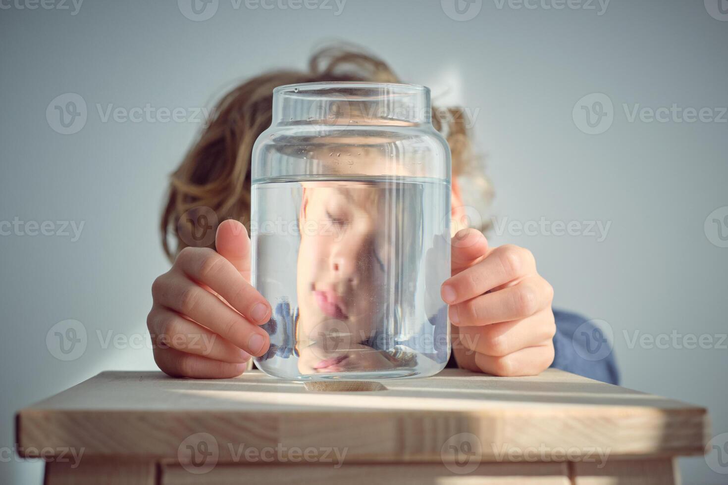 Sleepy boy reflection in glass jar with water photo