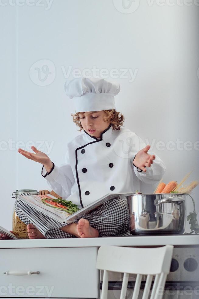 Puzzled preteen boy reading recipe of dish in cook book photo