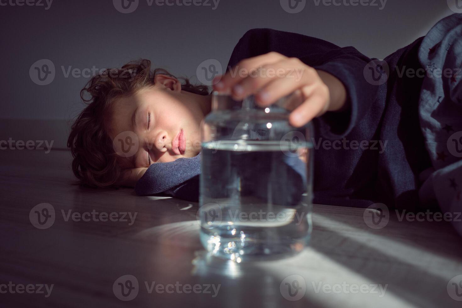 Calm boy in sunlight near glass bottle of water photo