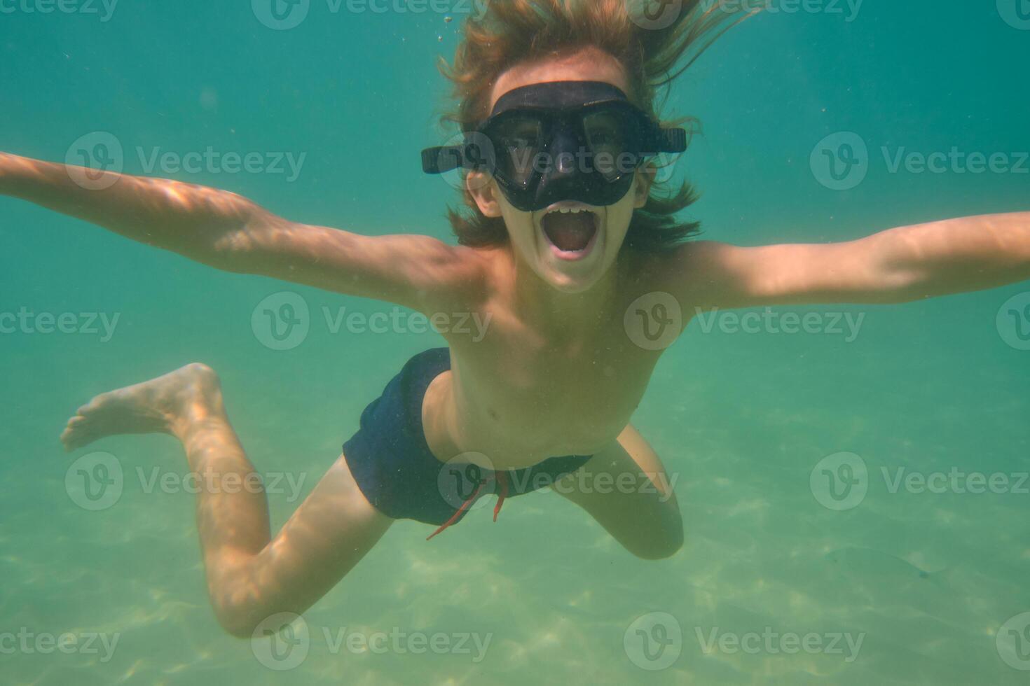 Boy with mouth opened swimming underwater photo