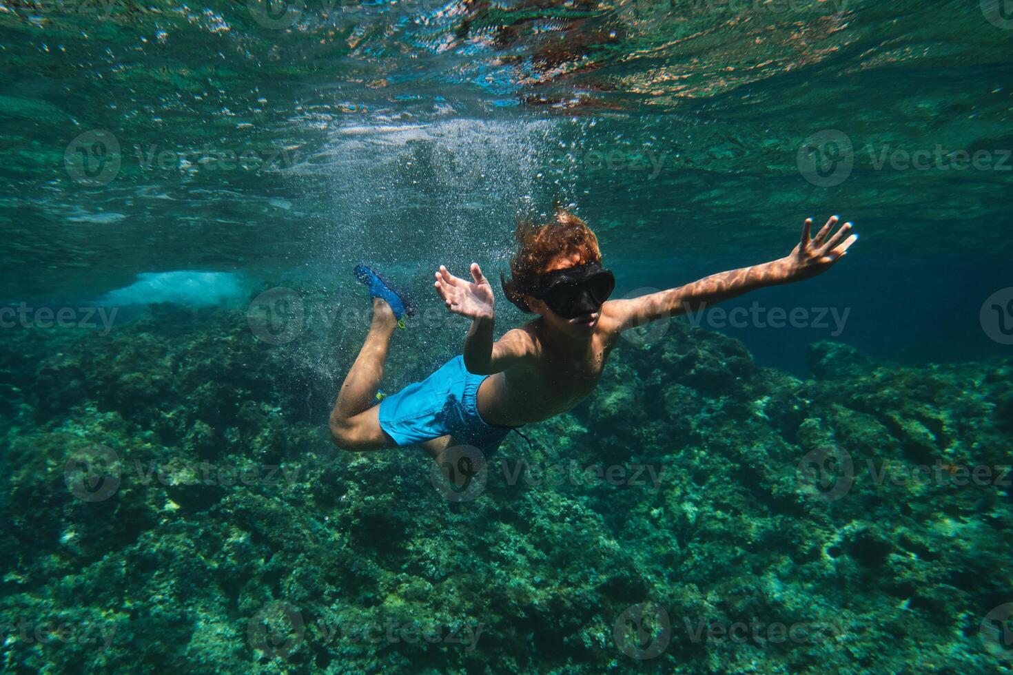 Boy in goggles swimming in ocean photo