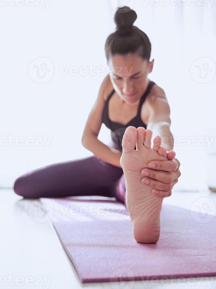 Woman sitting on mat and stretching legs photo