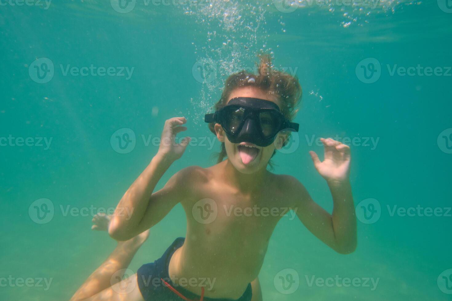 Boy having fun and showing tongue underwater photo