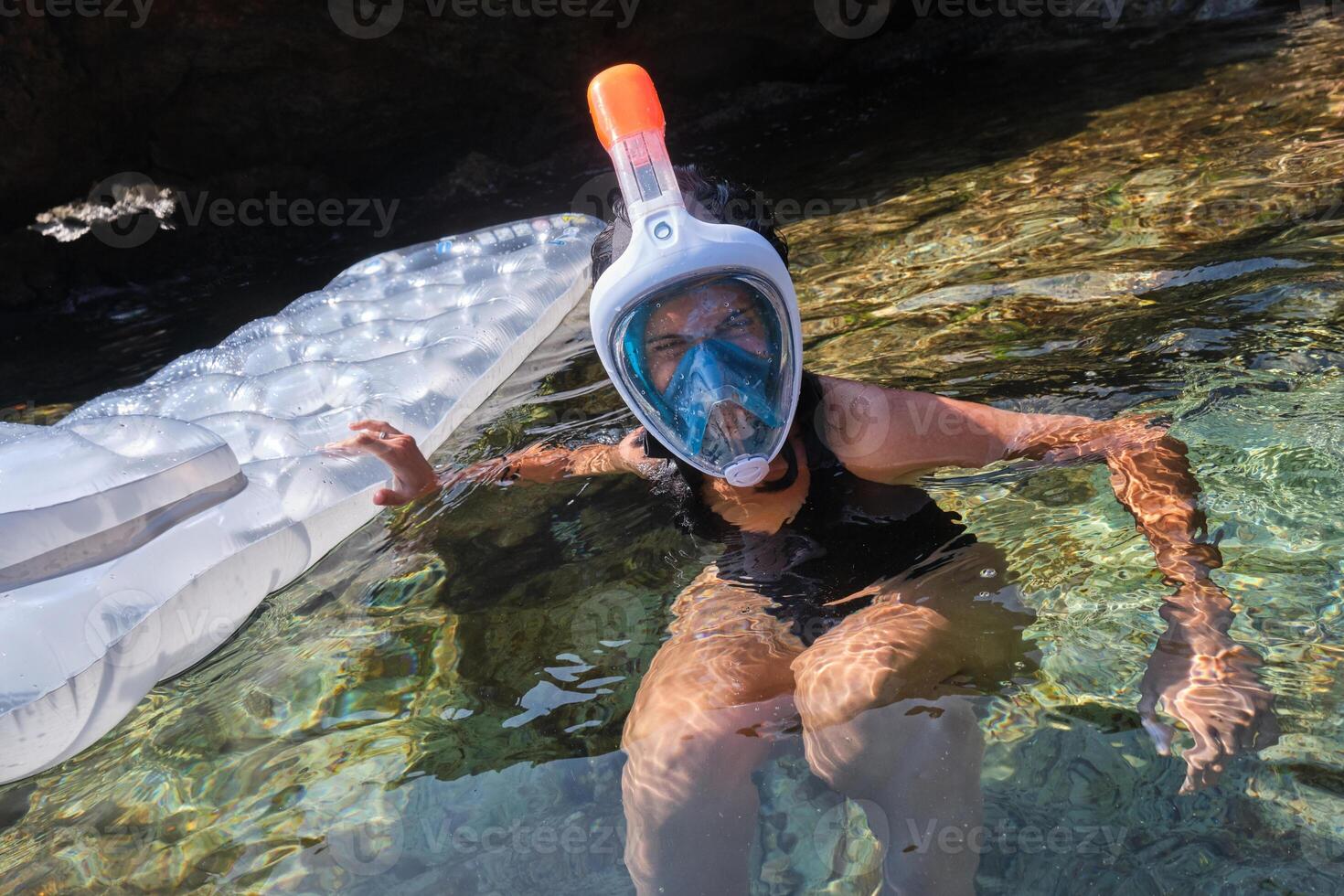 Woman in snorkeling mask swimming in sea photo