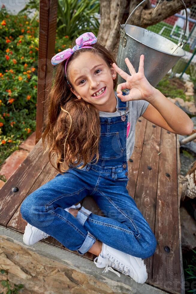 Smiling girl showing OK gesture on bench photo