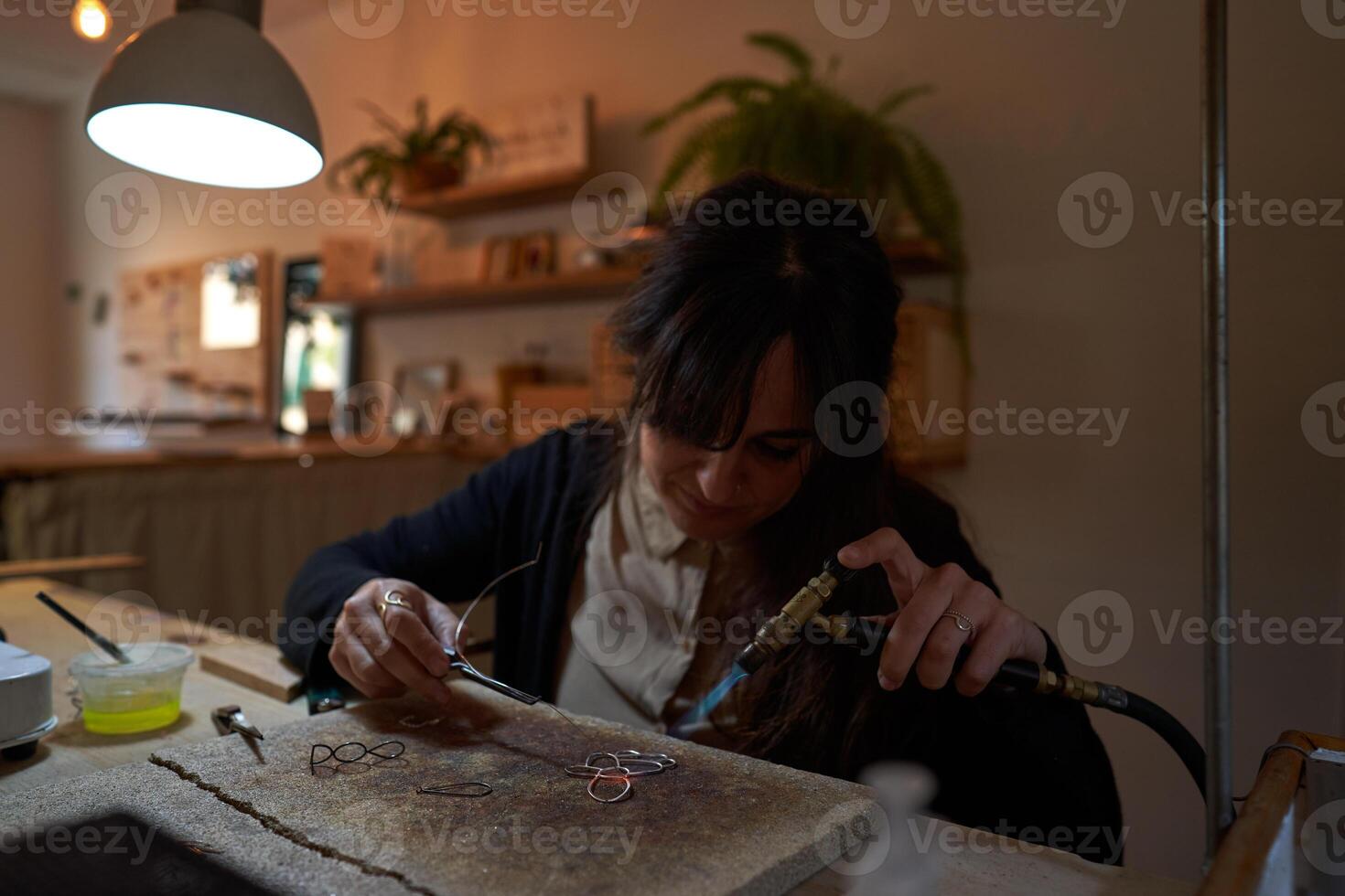 Focused female artisan creating handmade accessories in workshop photo