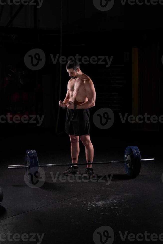 Man sportsman preparing for lifting barbell with plates photo