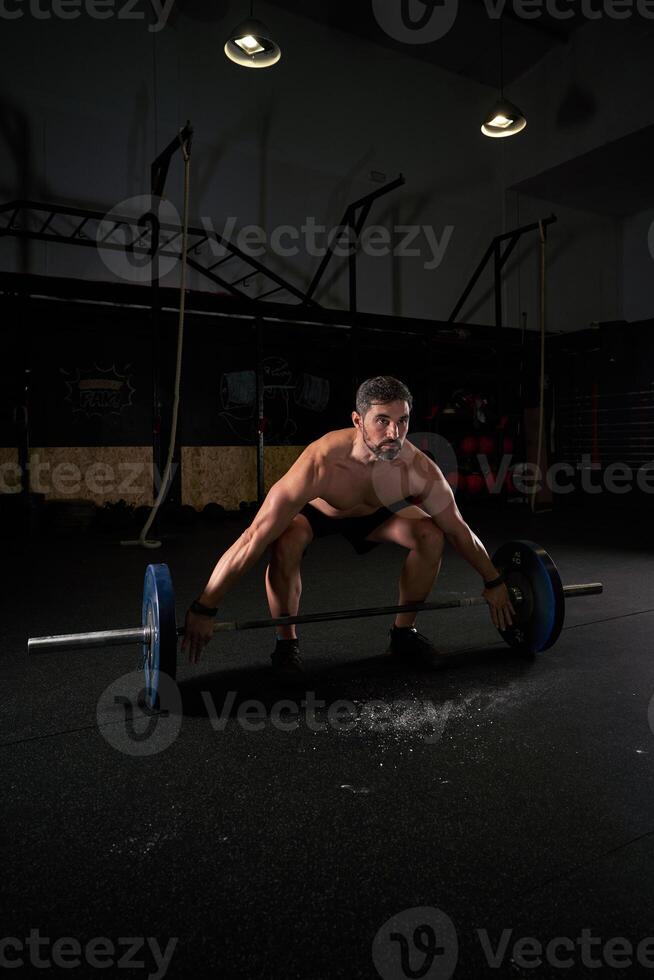 Strong concentrated man training with barbell photo