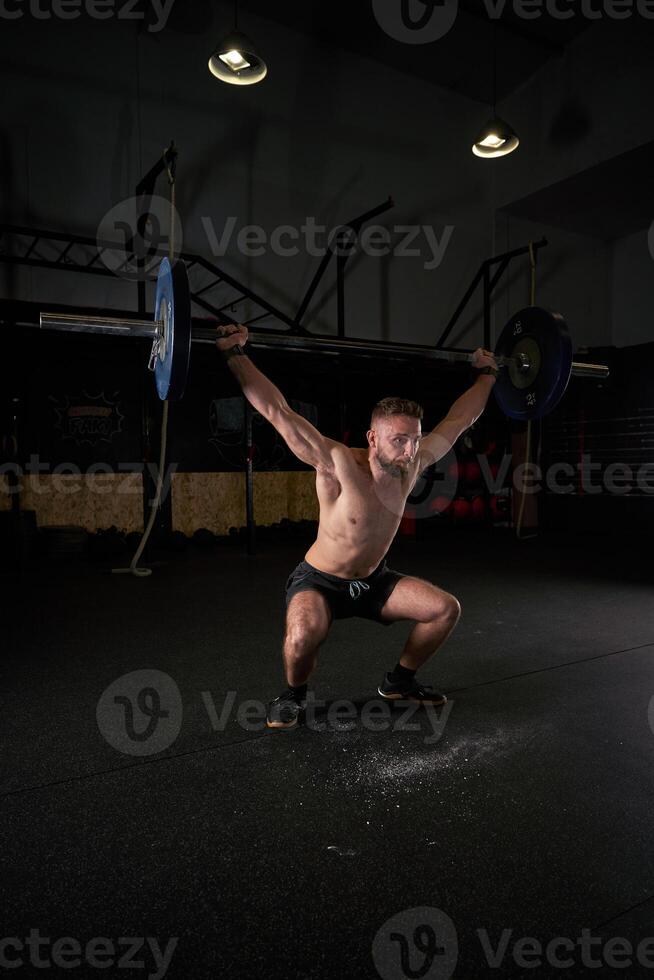 Strong sportsman doing weightlifting exercise with barbell photo