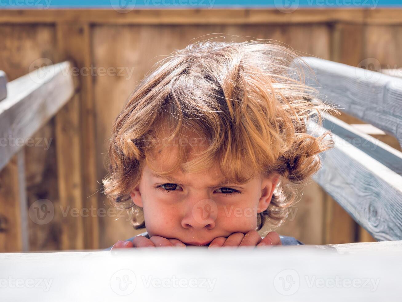 Unsatisfied kid looking down from playground photo