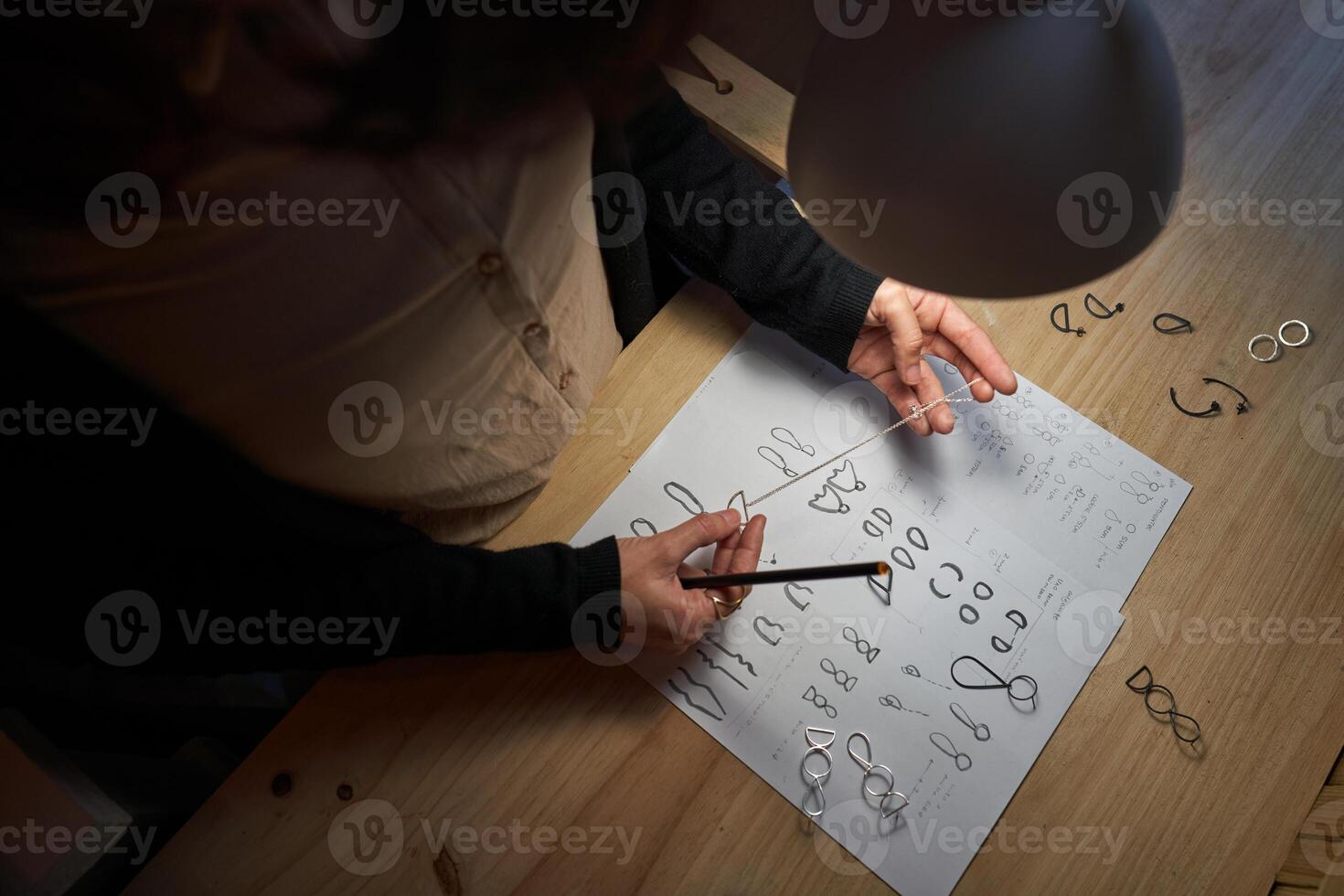 Crop master holding pendant above table with images and jewelry photo