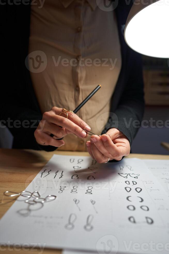 Crop goldsmith working at table under lamp photo