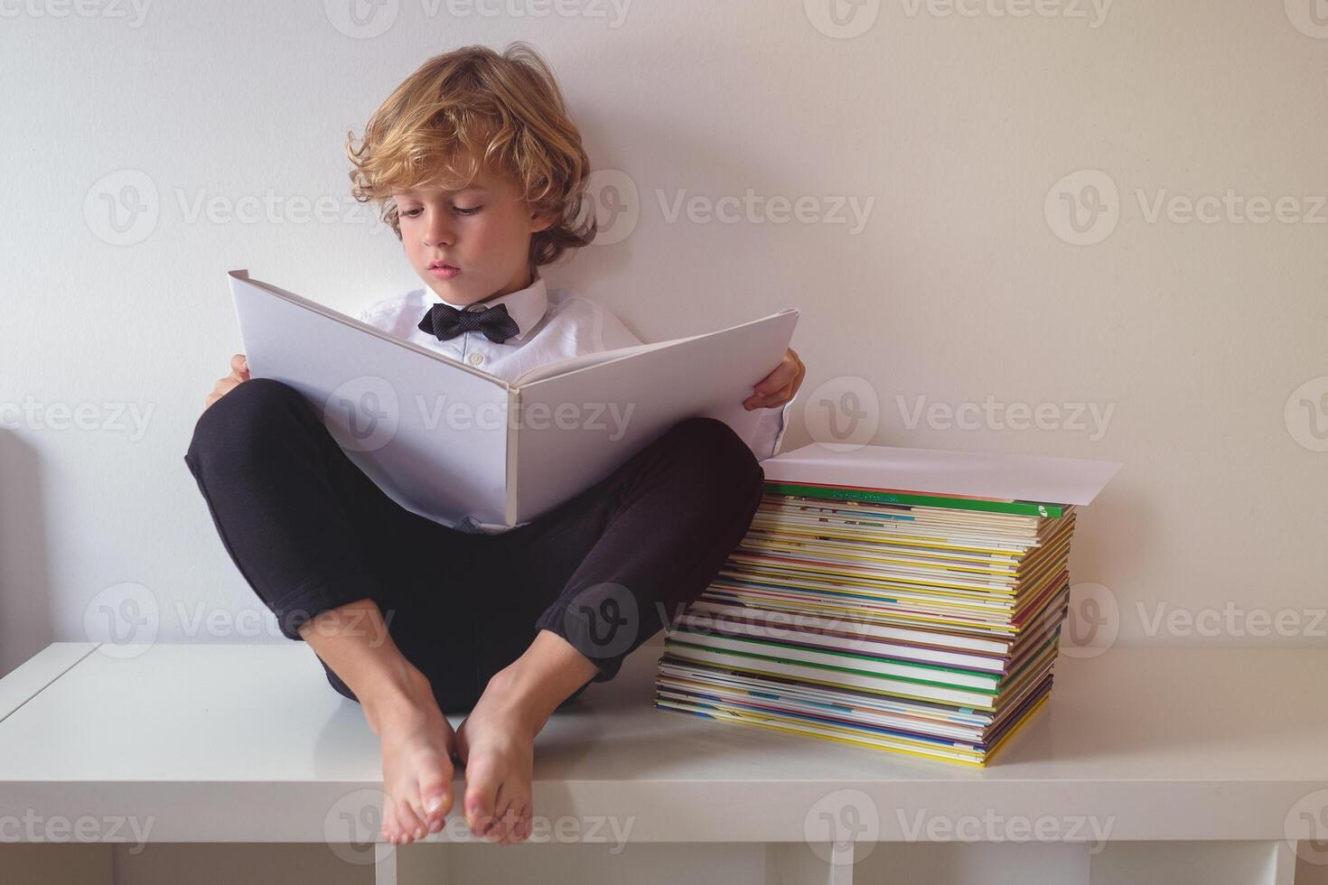 Focused boy in suit reading book photo