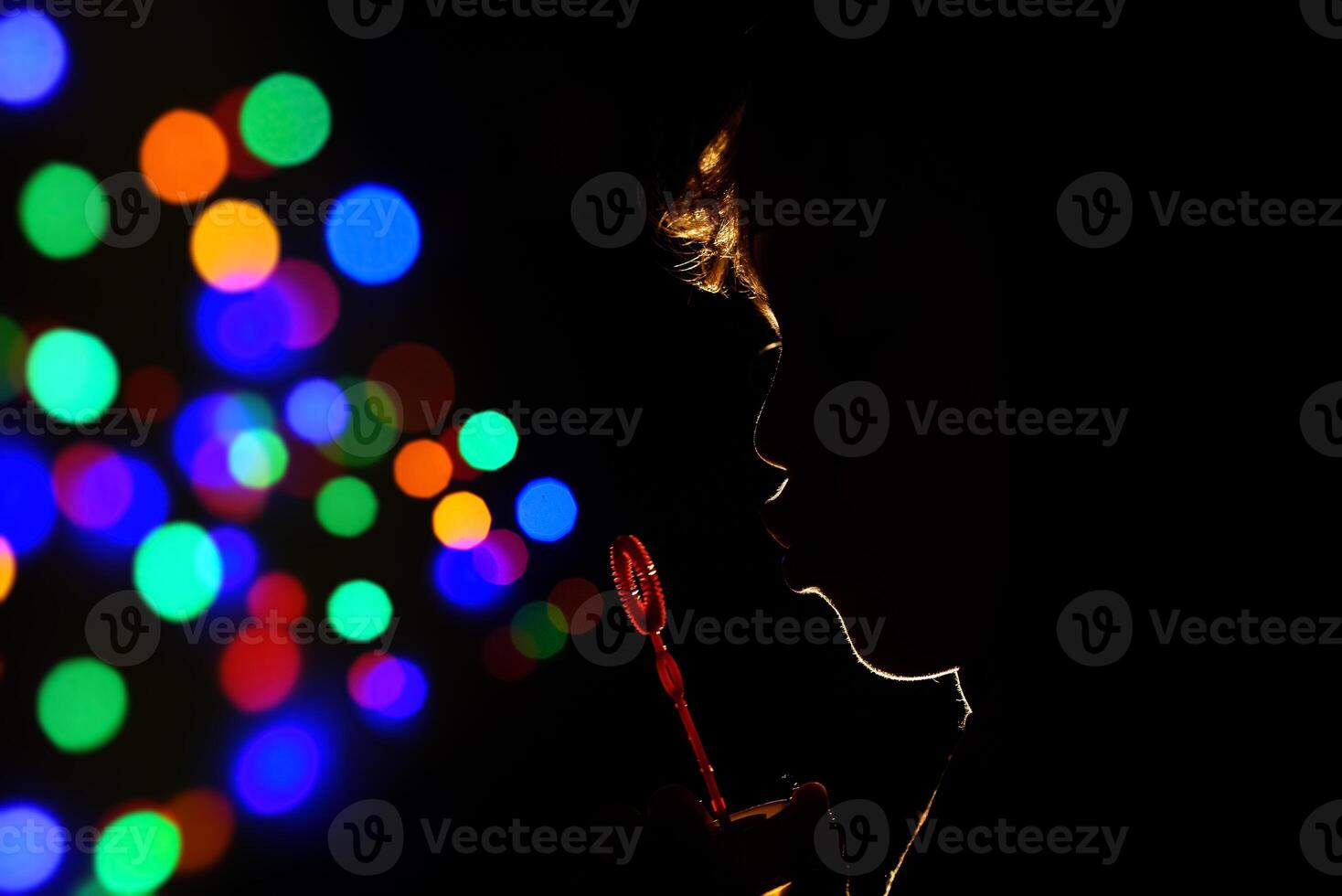 Anonymous kid blowing bubbles in darkness photo