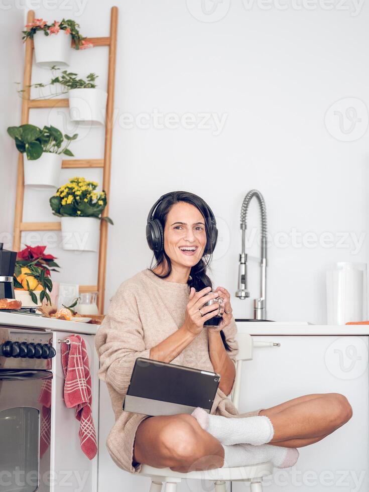 Female in headphones using tablet while relaxing with coffee photo