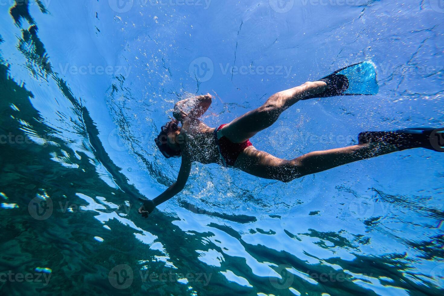Preteen boy swimming underwater in flippers and snorkeling mask photo