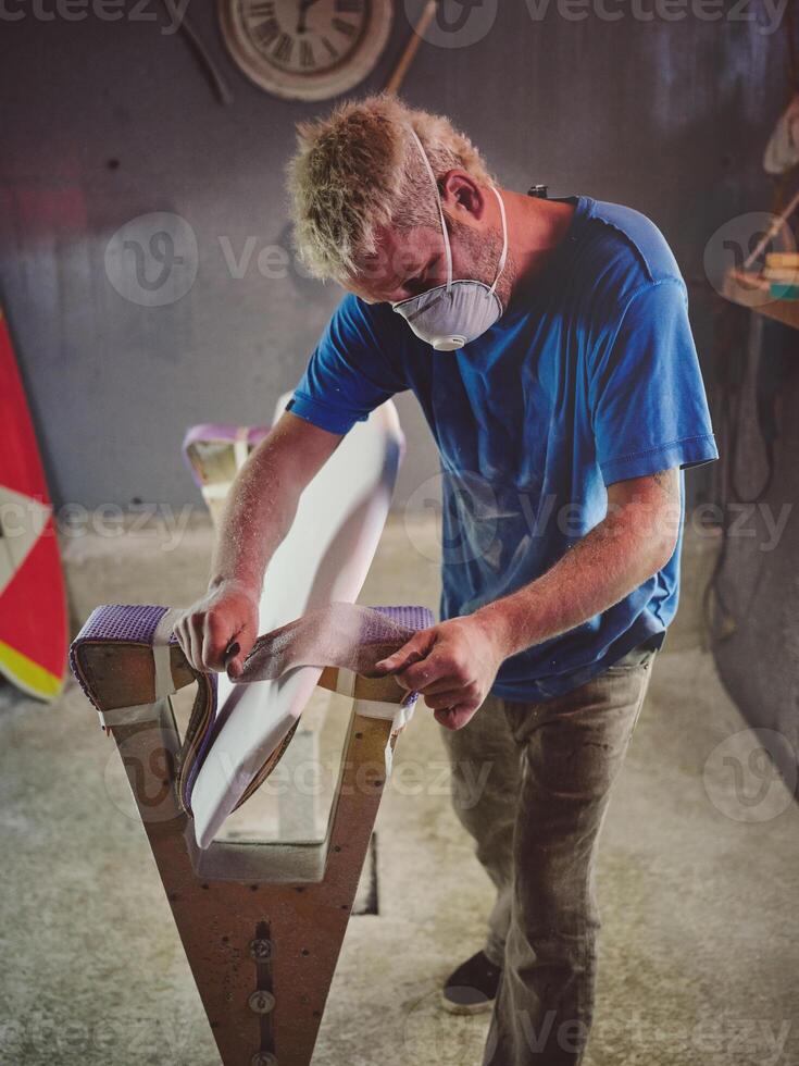 Attentive male surfboard shaper polishing template edges with sa photo