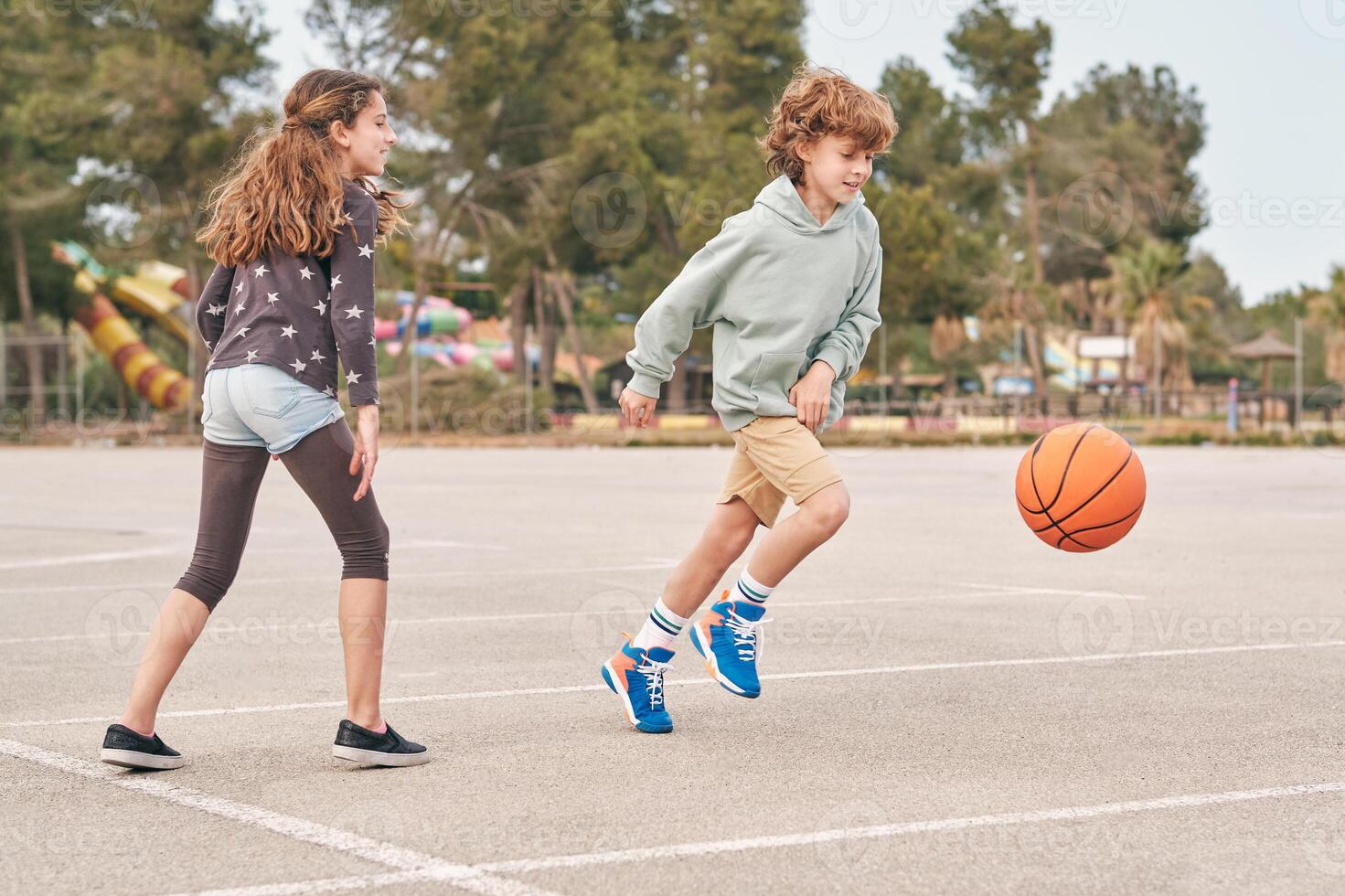 Content teen boy and girl playing basketball in city photo
