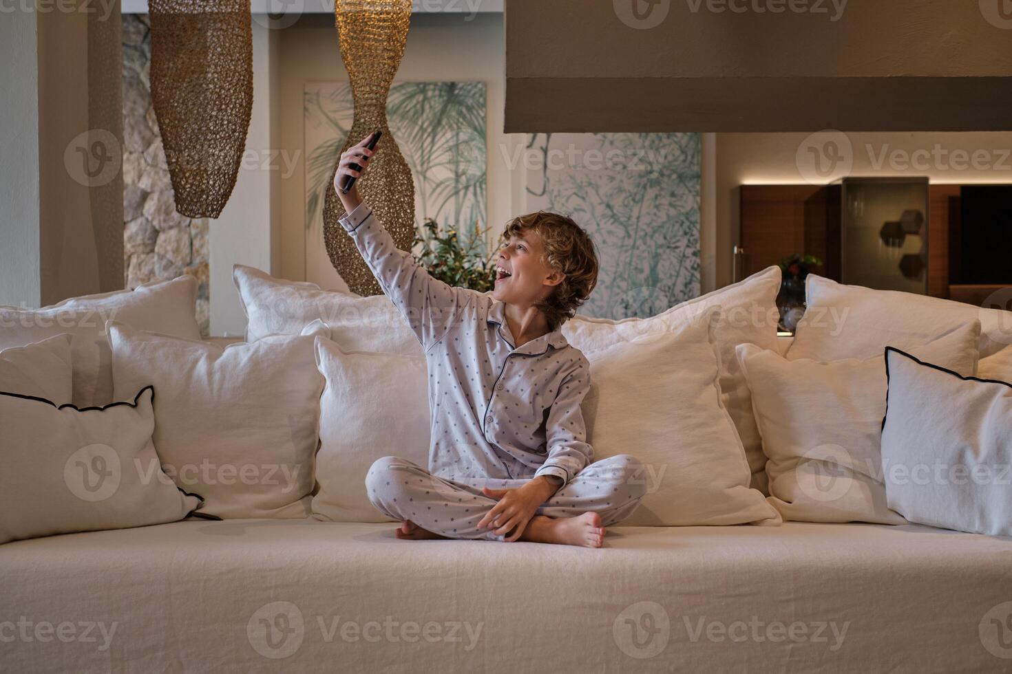 Excited boy taking selfie on sofa at home photo