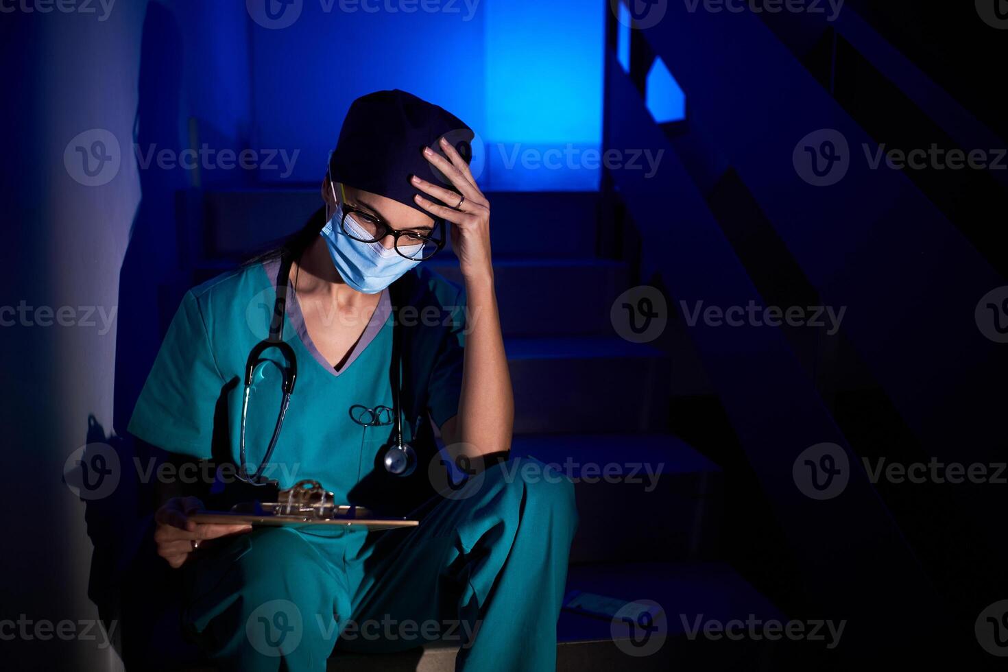 Pensive female doctor sitting on stairs photo