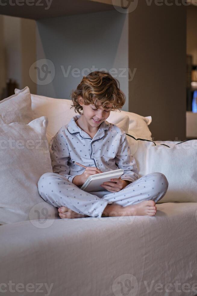 Cheerful boy in pajama doing homework photo