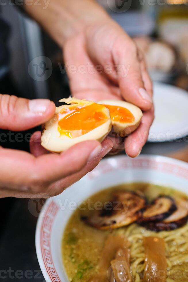 Crop person adding boiled eggs to ramen photo