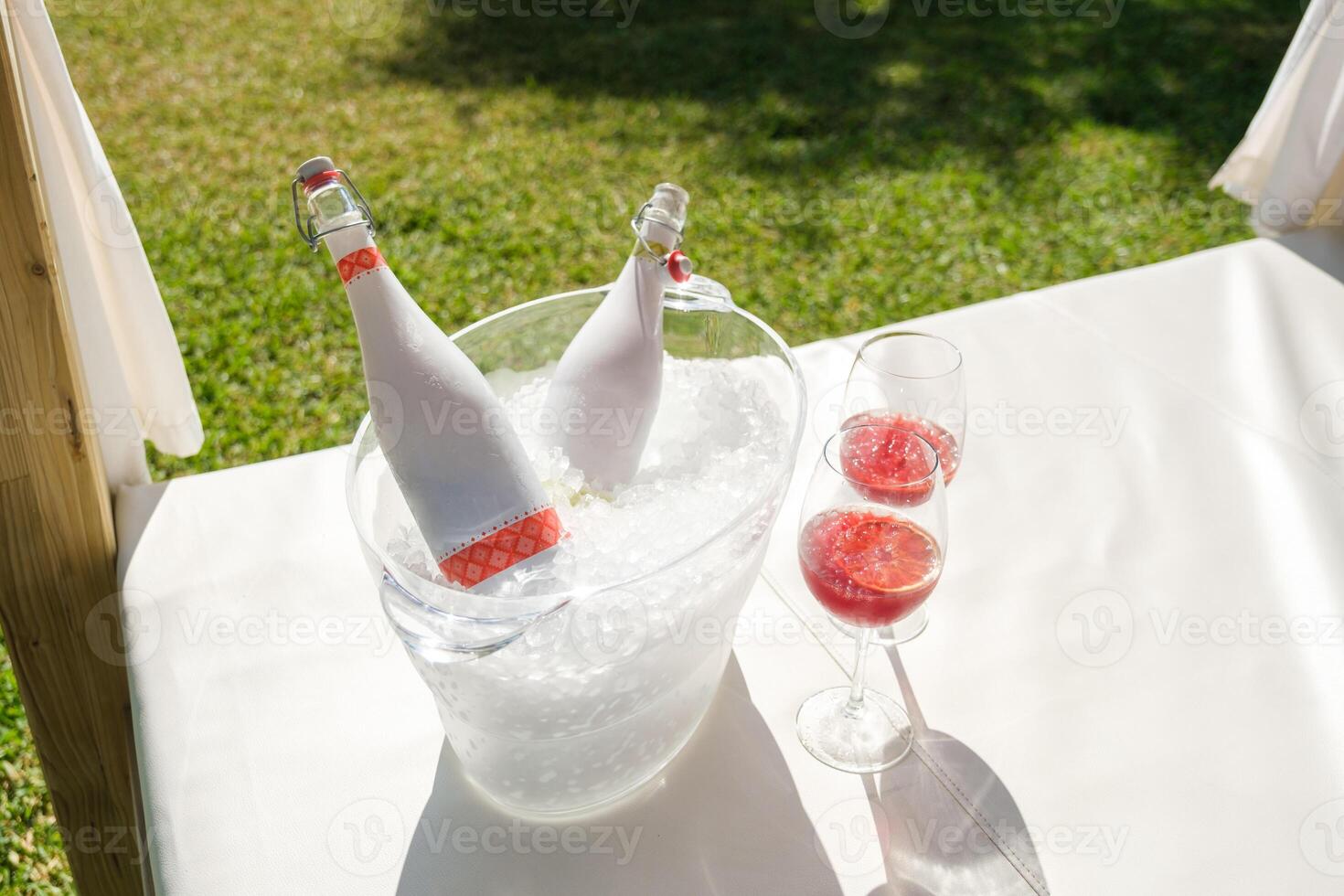 Bottles and glasses with wine on canopy bed photo
