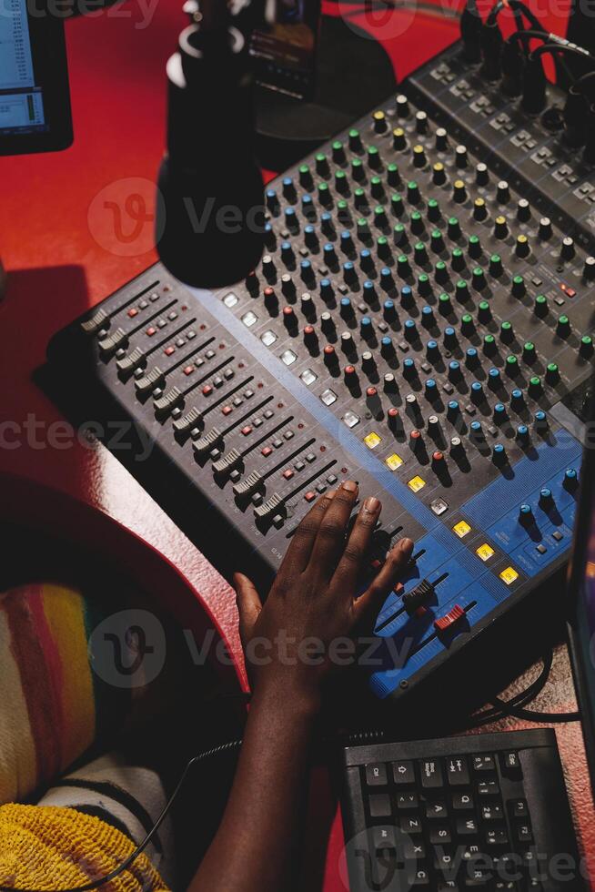 Crop black person working with mixing console in studio photo