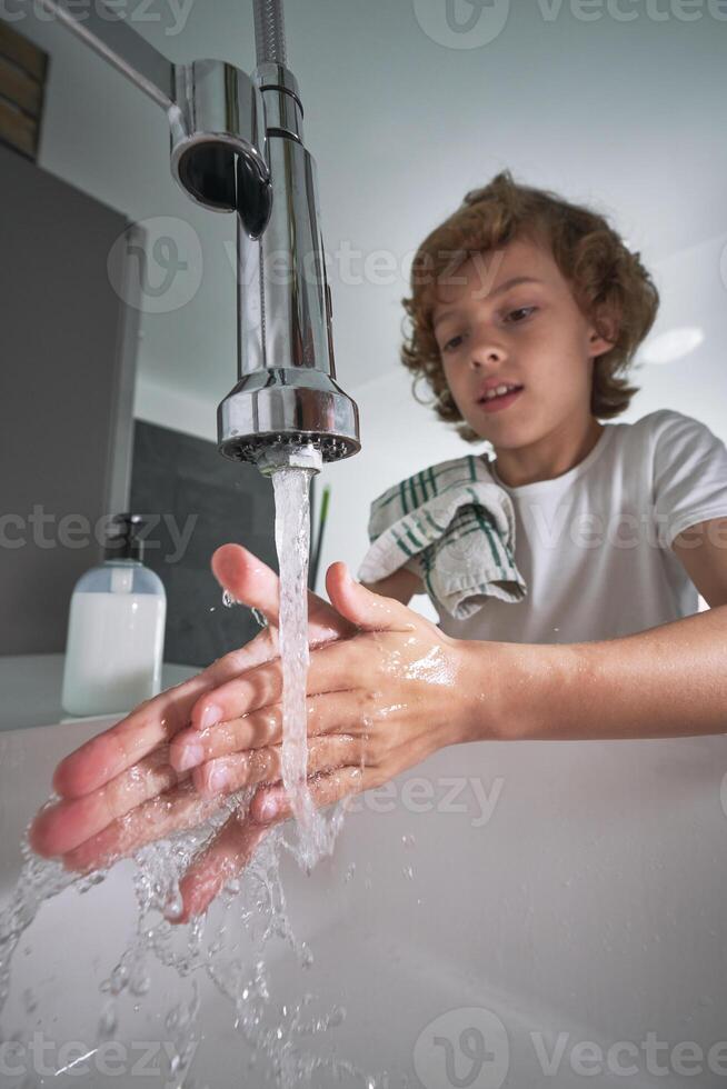 Boy washing hands in bathroom photo