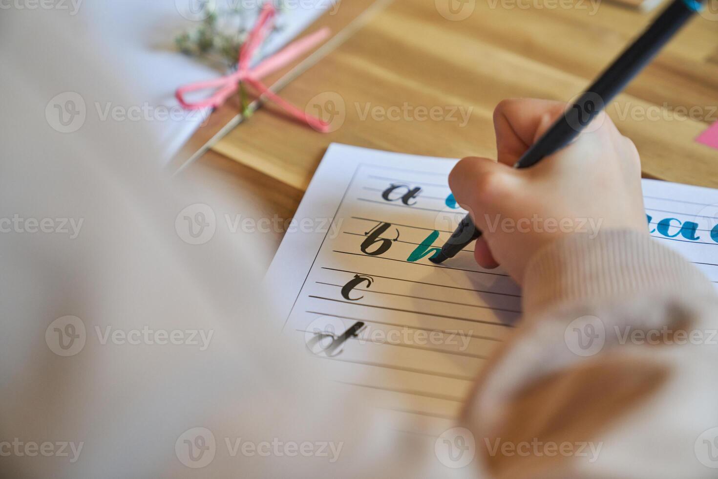 Crop unrecognizable artist drawing letters sitting at wooden table photo