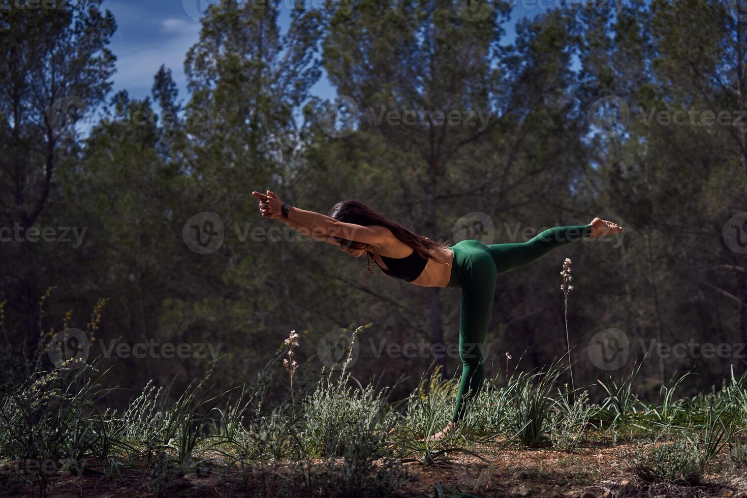 Faceless woman doing Warrior III asana in nature photo