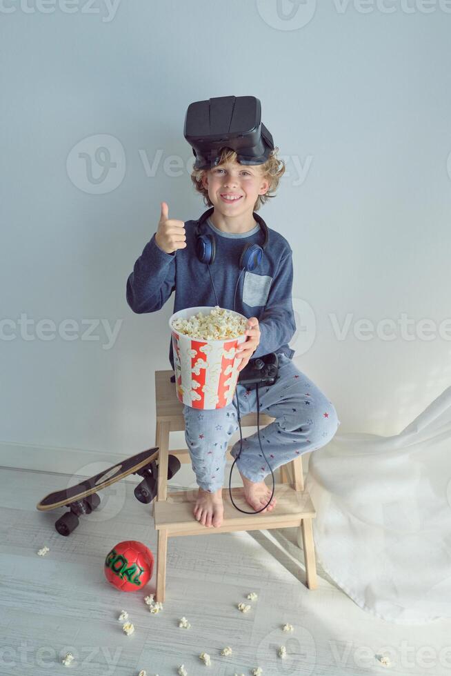 Boy with VR goggles and popcorn showing thumb up sign photo