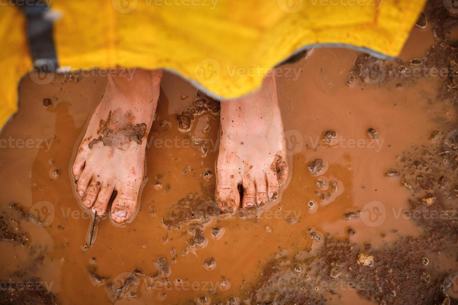 Dirty feet of crop person in puddle photo