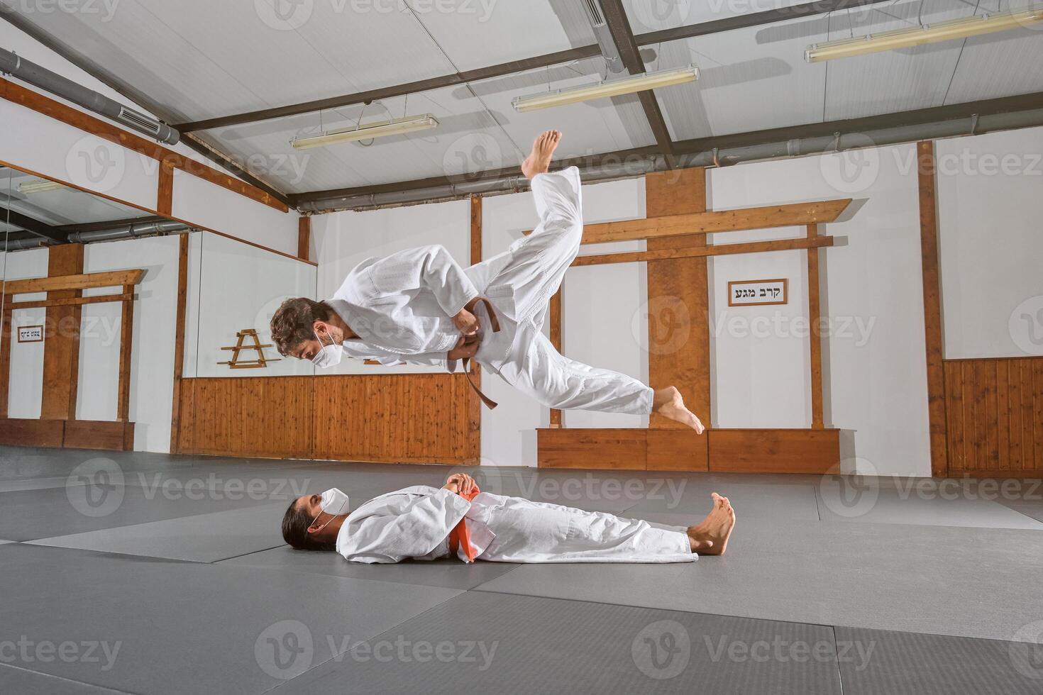 Two people with mask and kimono practicing krav maga photo