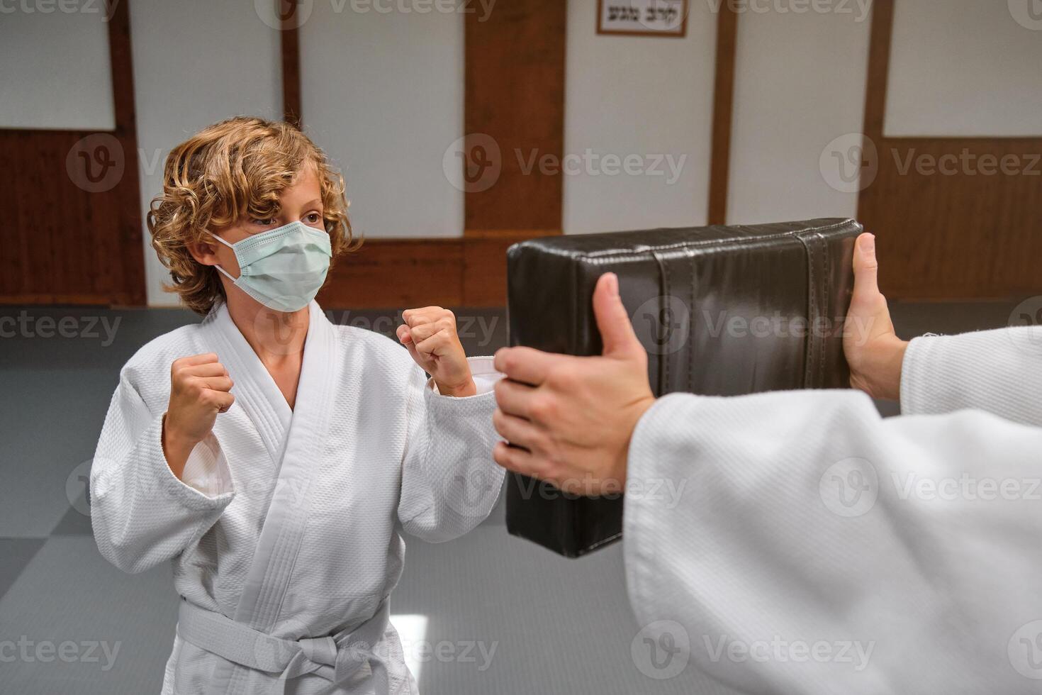 Boy in mask doing karate in dojo photo