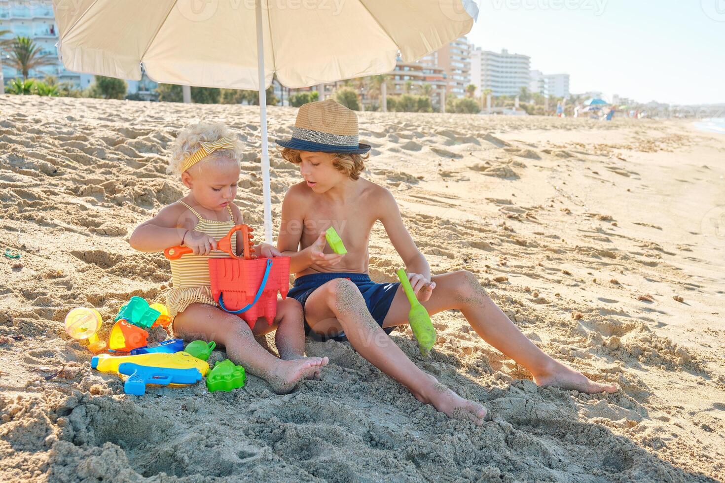 Little boy and girl playing with toys on beach photo