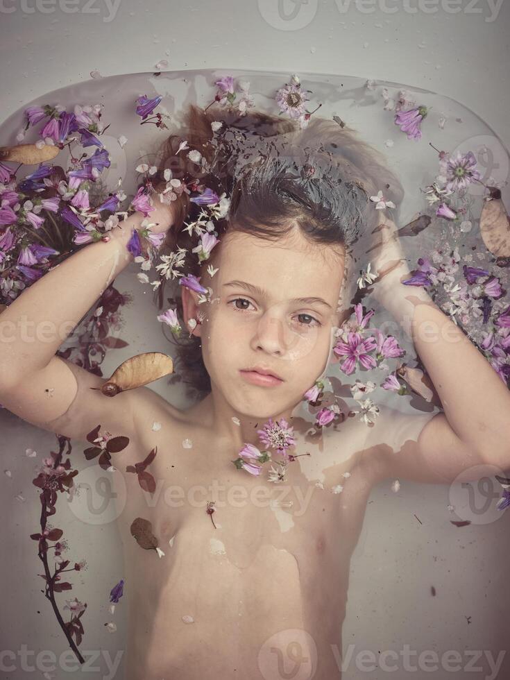 Boy in bathtub with colorful flowers photo