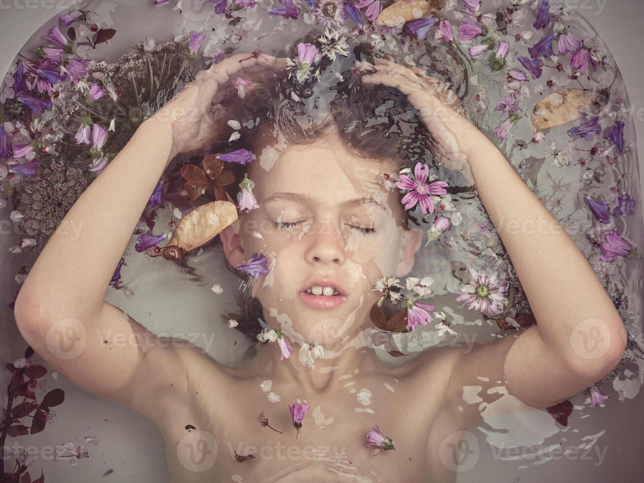 Boy underwater in bathtub with flowers photo