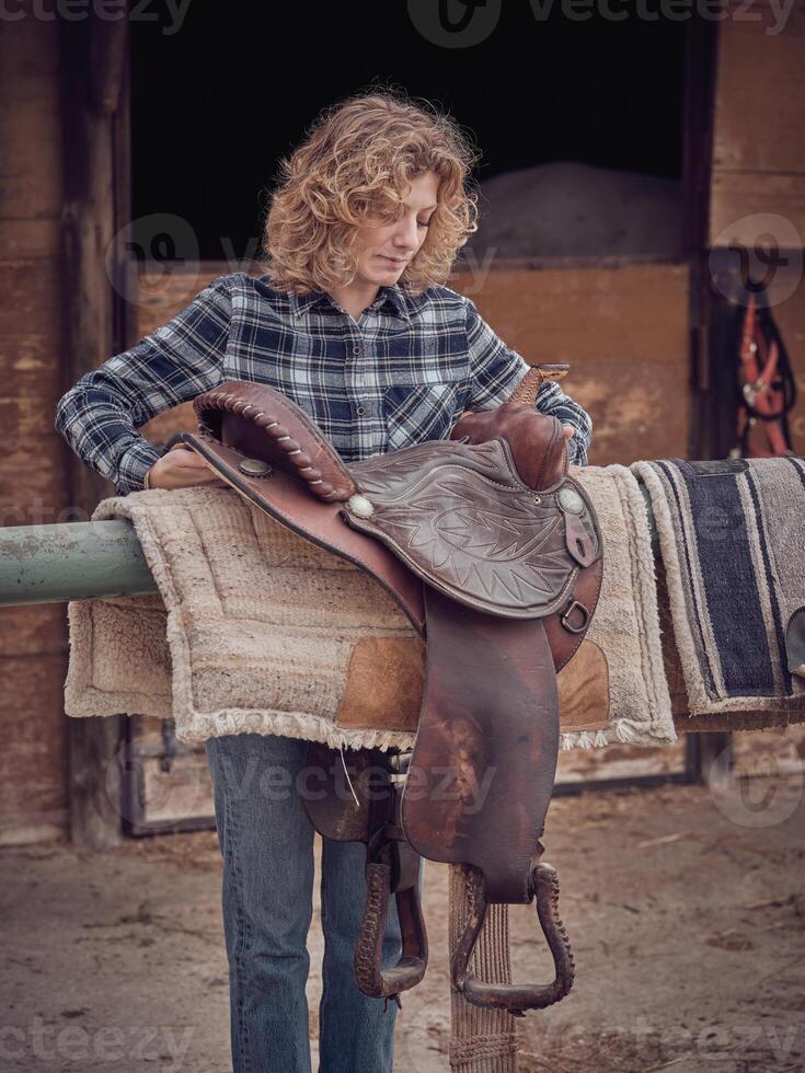 Woman putting saddle on railing photo