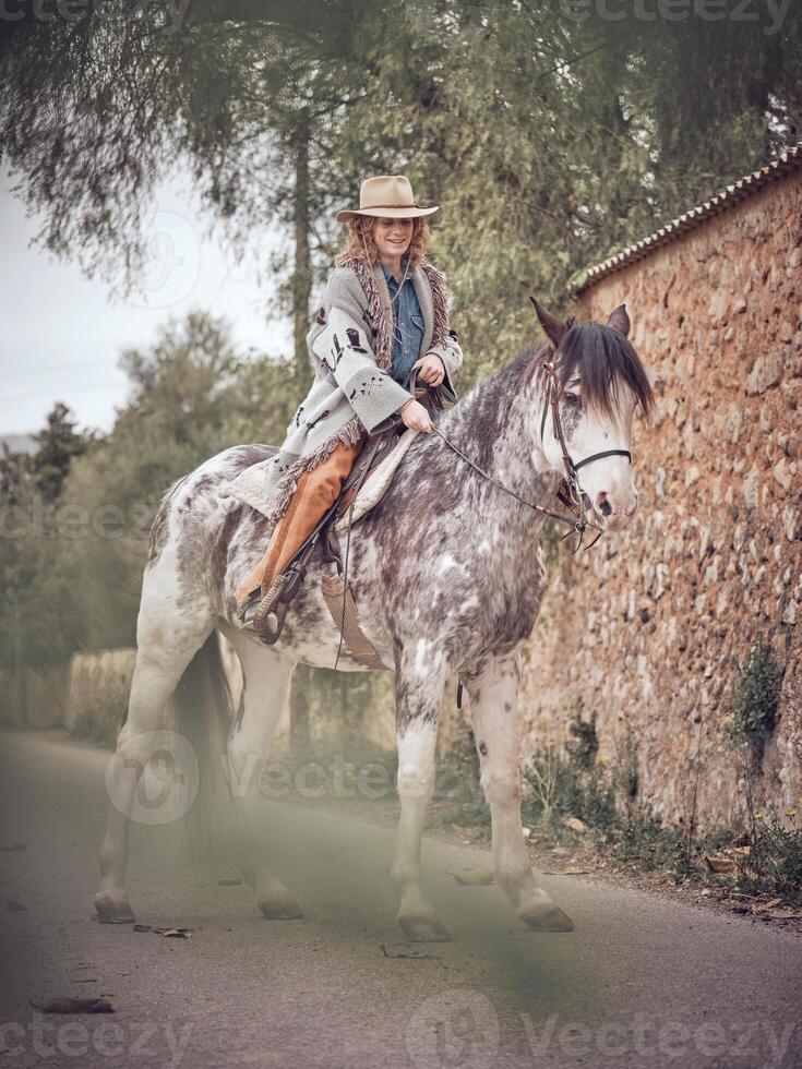 Smiling adult female equestrian sitting on gray horse photo