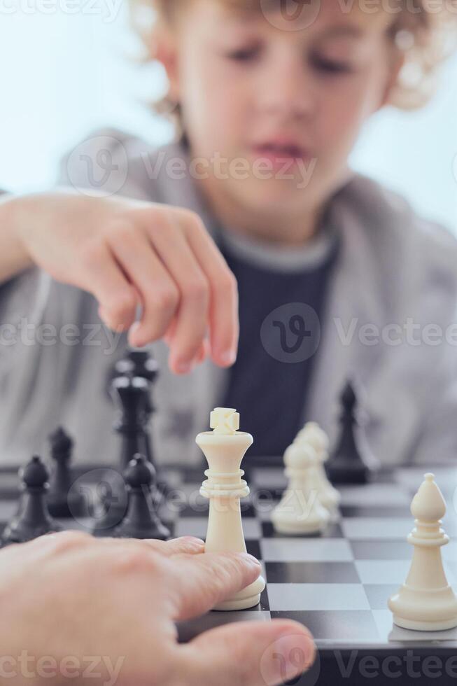 Anonymous person playing chess with boy photo