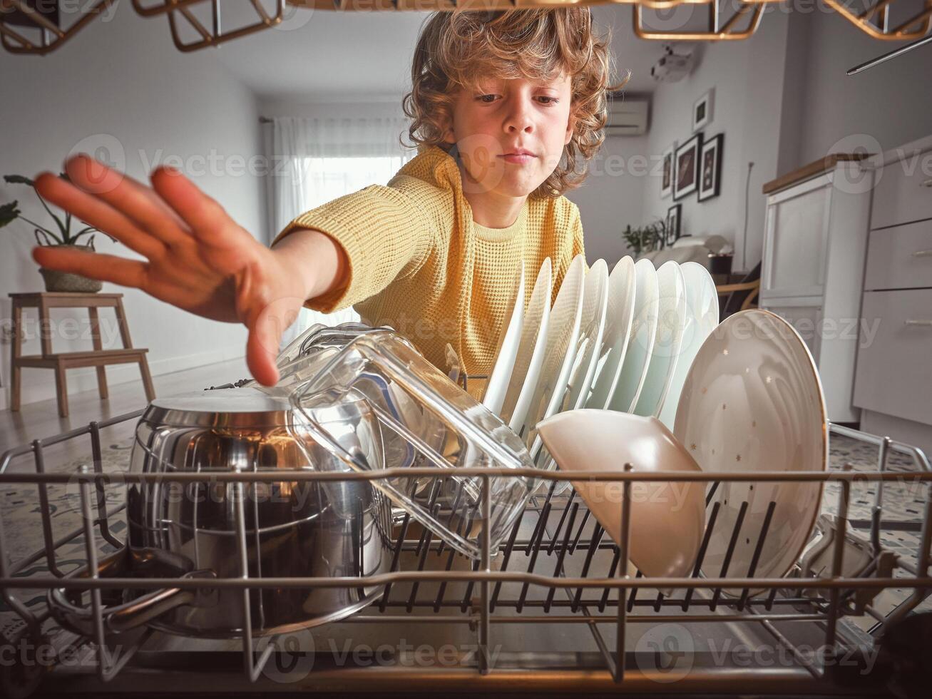 Boy unloading dishwasher with dishware photo