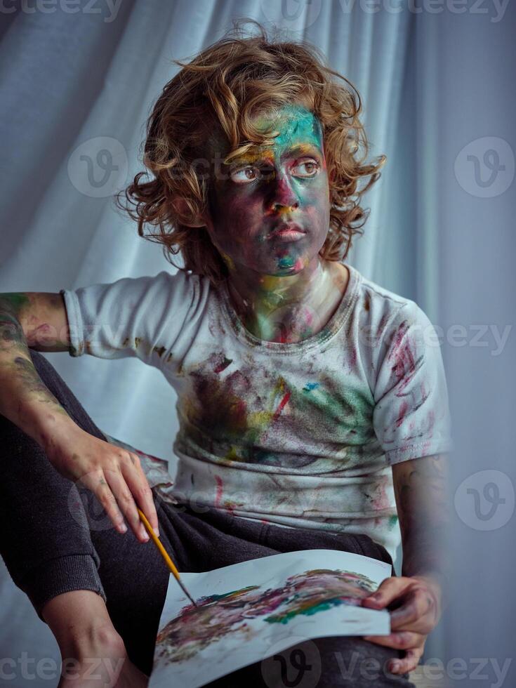 Boy with painted face looking away and drawing photo