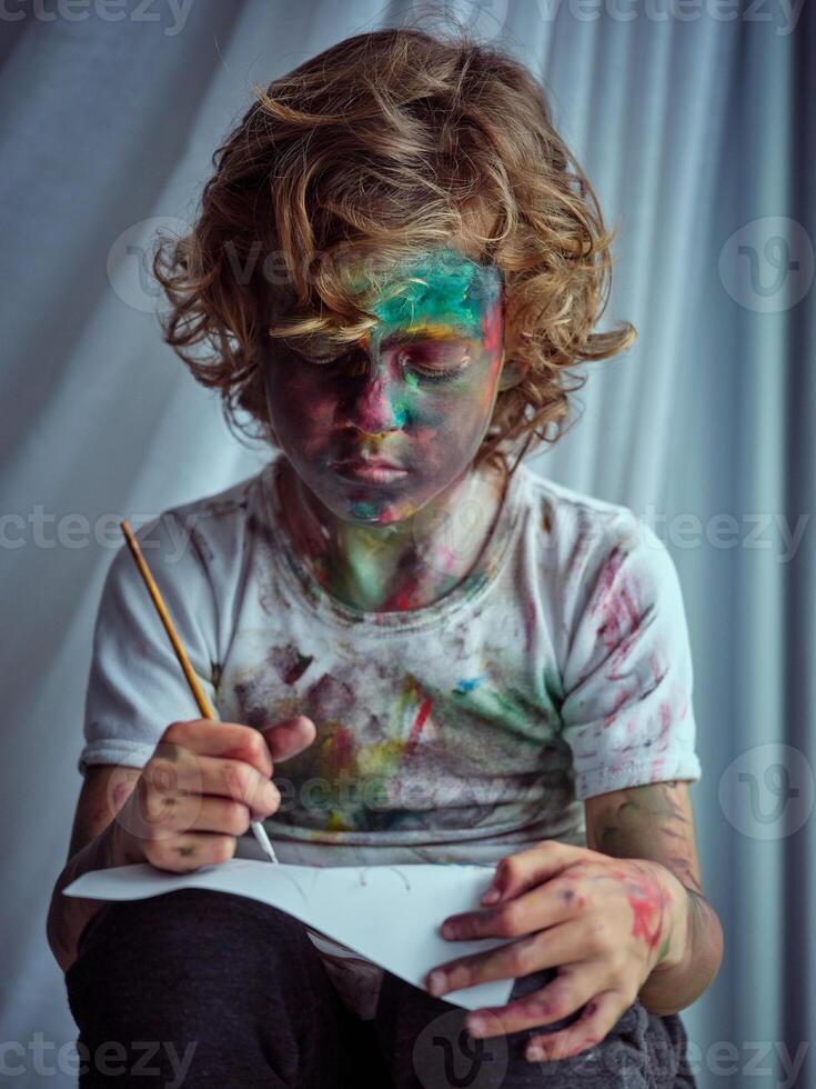 Little artist looking at paper and engrossed in painting photo
