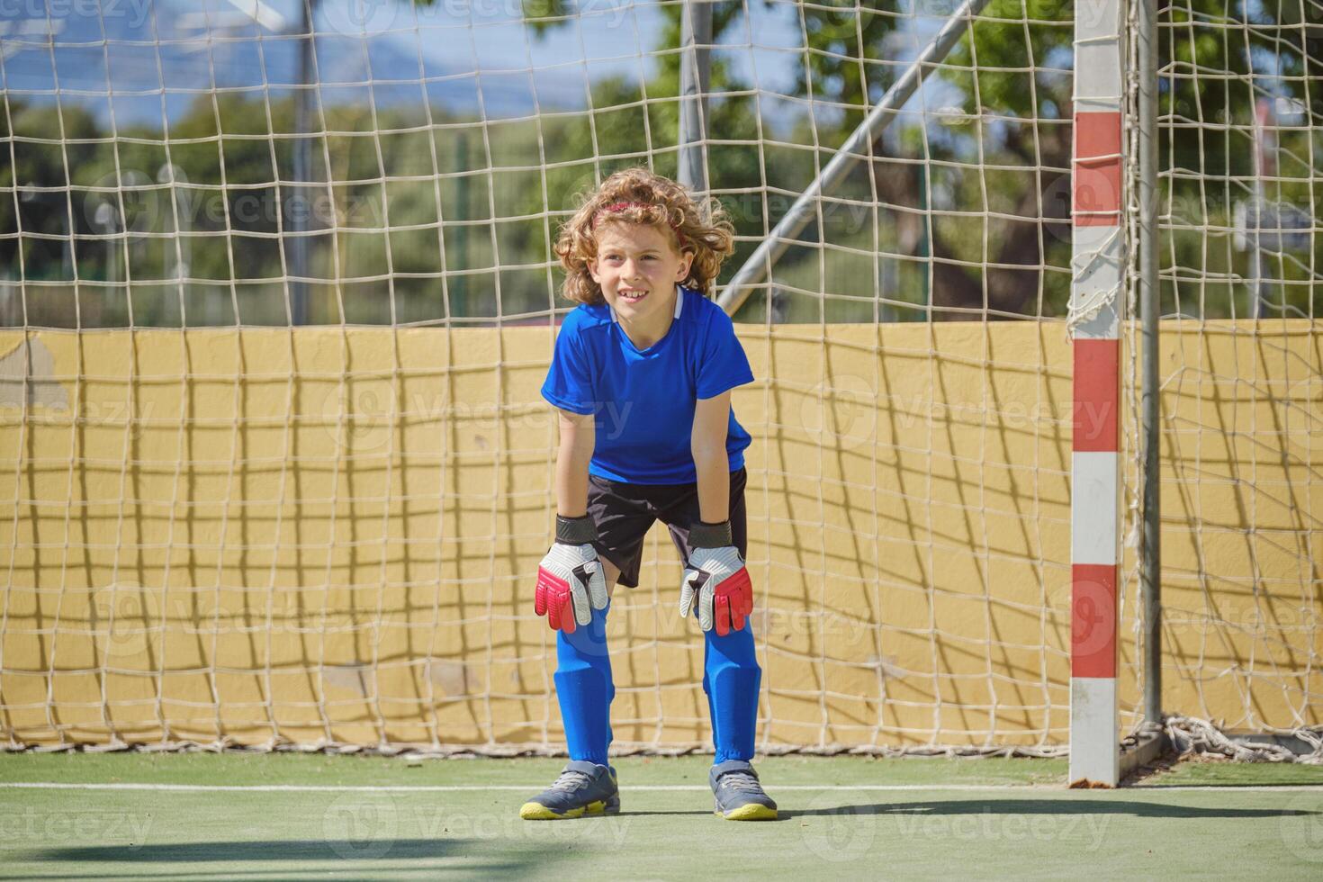 Happy boy standing at football goal photo