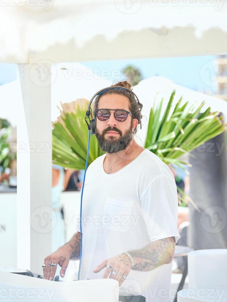 Ethnic man working on DJ controller on terrace in sunlight photo