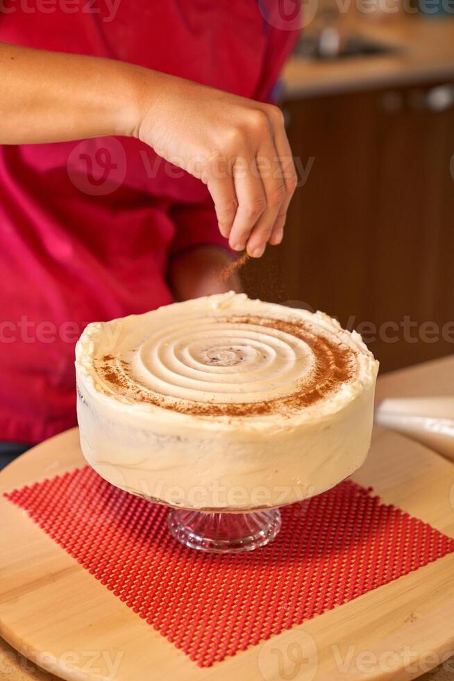 Crop female sprinkling cake with cinnamon powder photo